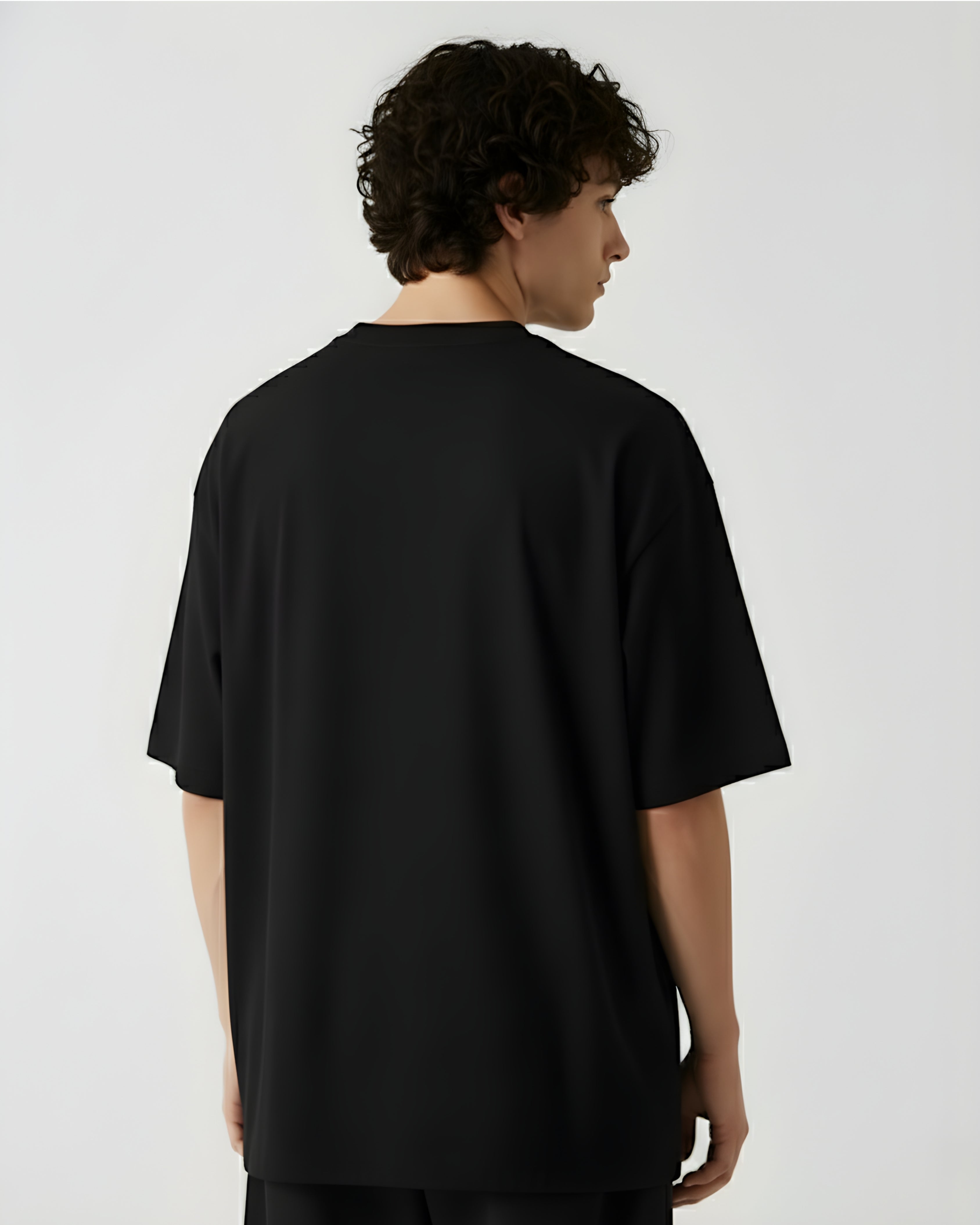Person wearing a dark OVERSIZE Tshirt against a white background