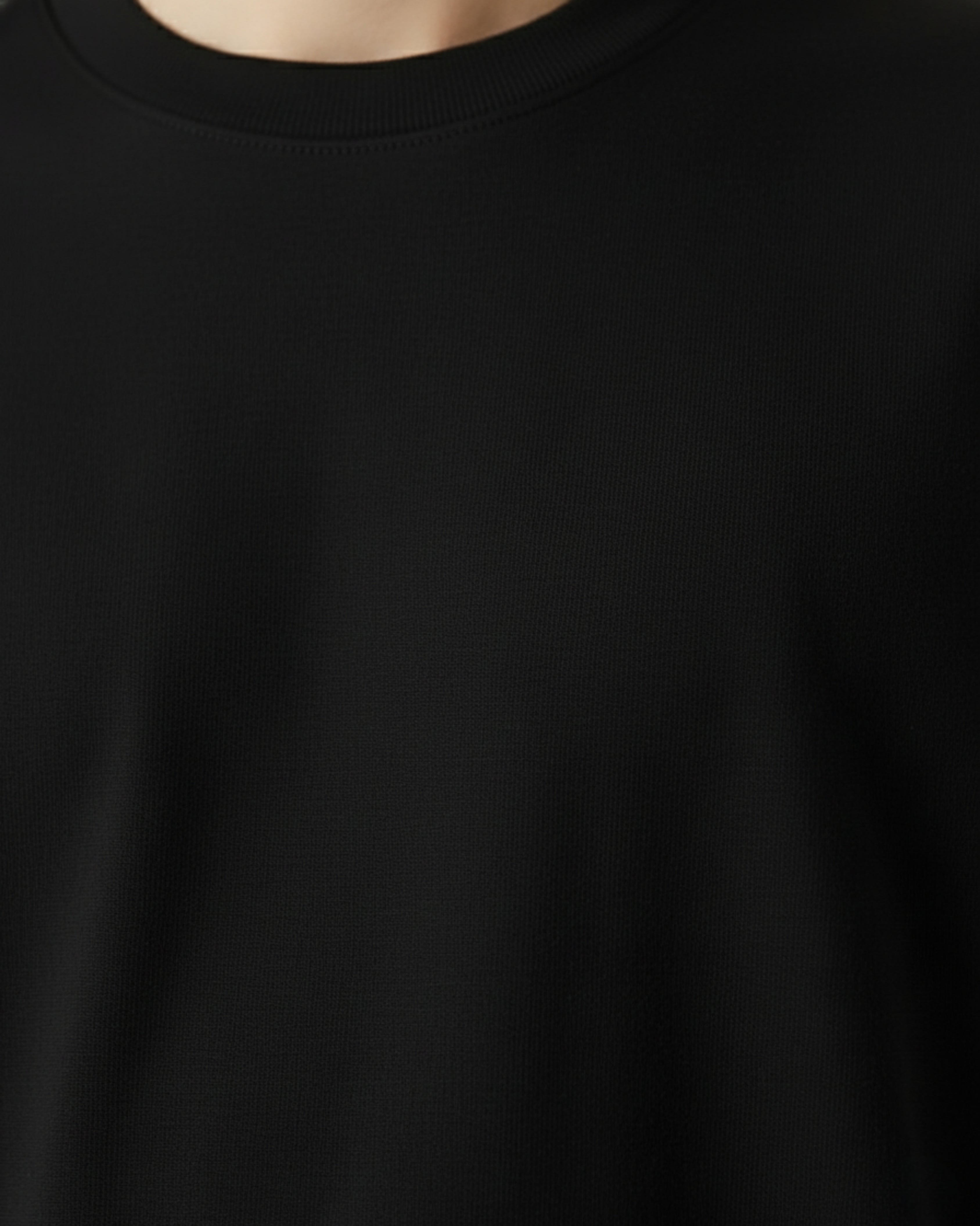 Close-up of a plain black t-shirt with a blurred background