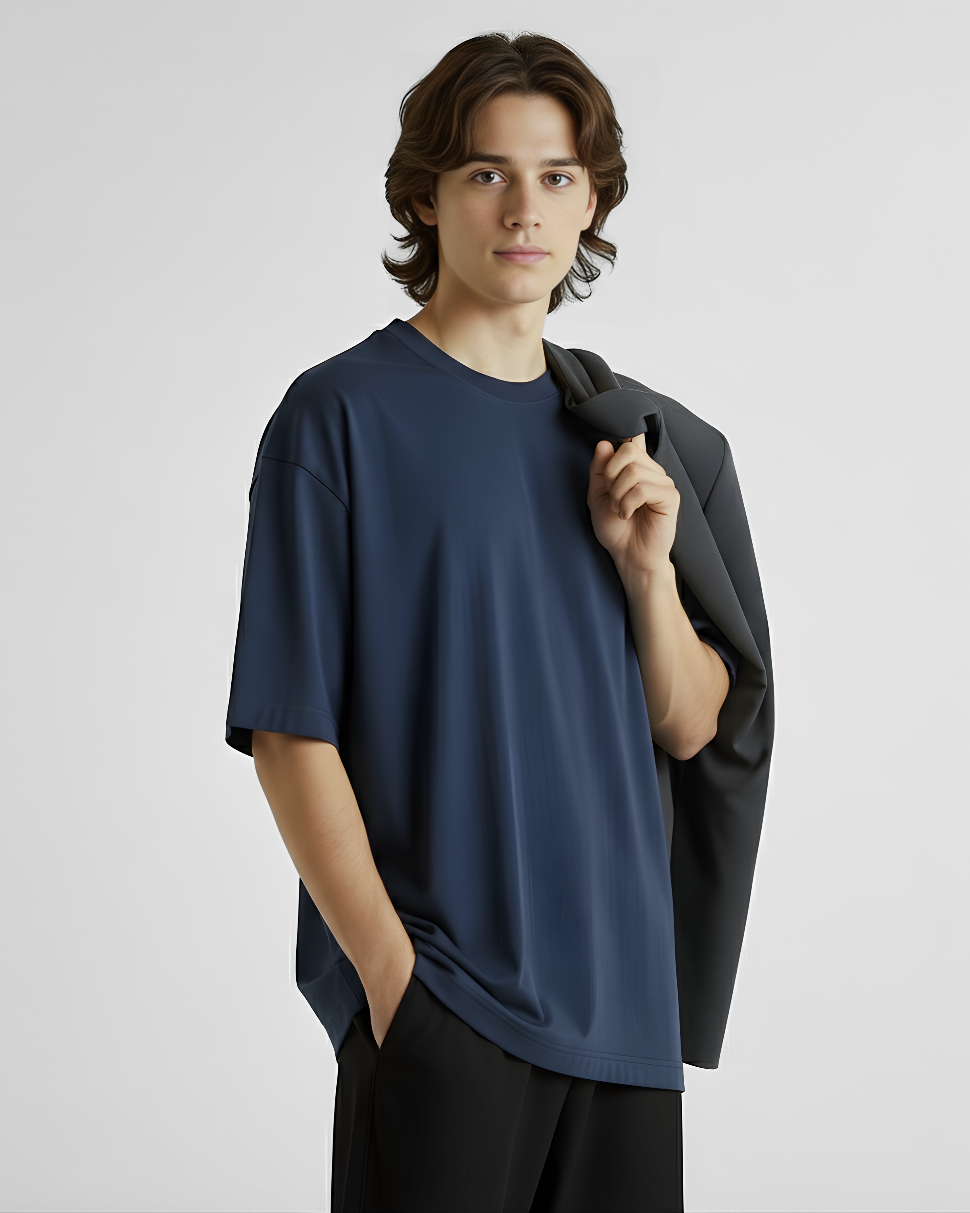 Man wearing a navy blue oversized t-shirt and black pants against a plain background