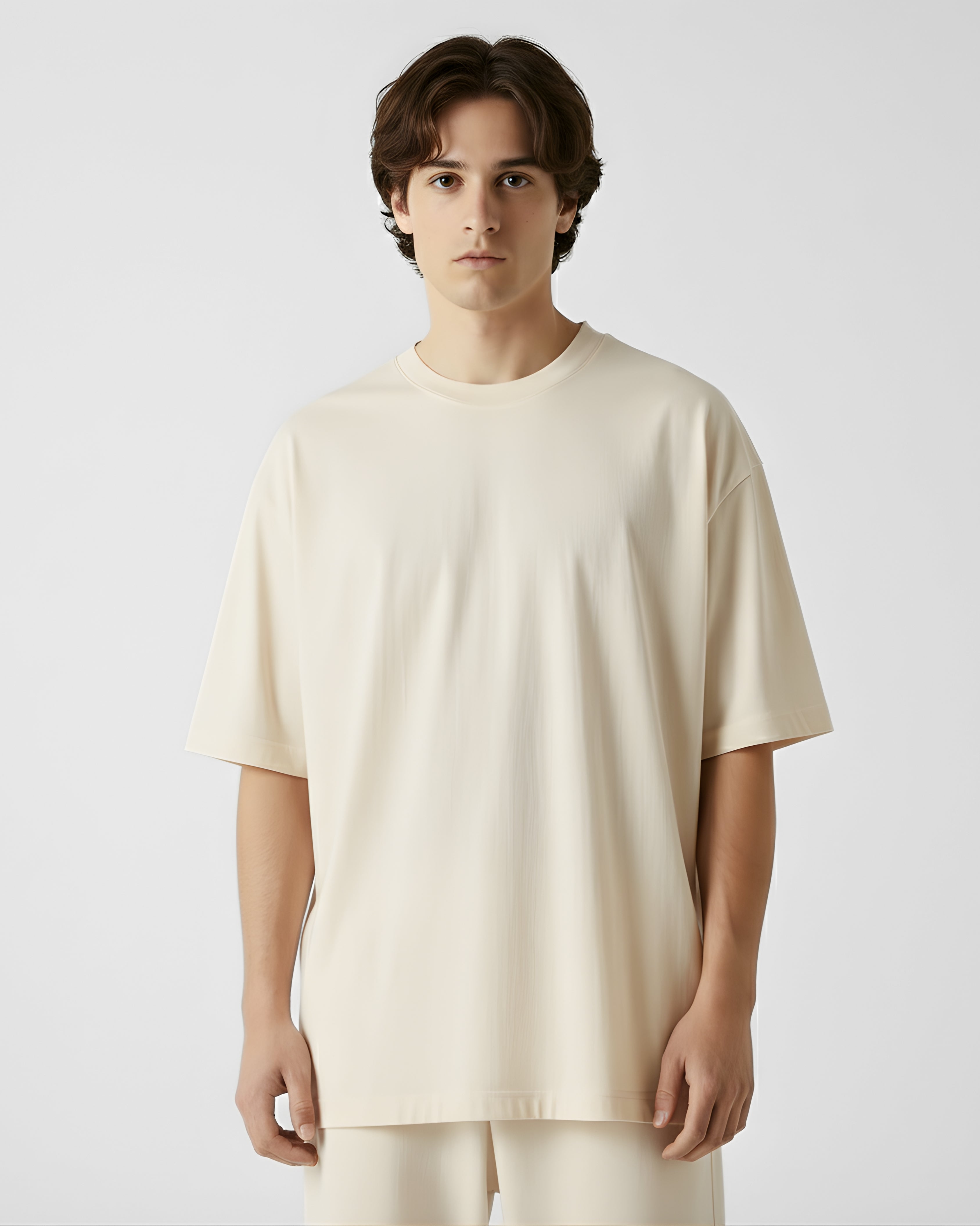 Person wearing a cream oversizetshirt against a plain background