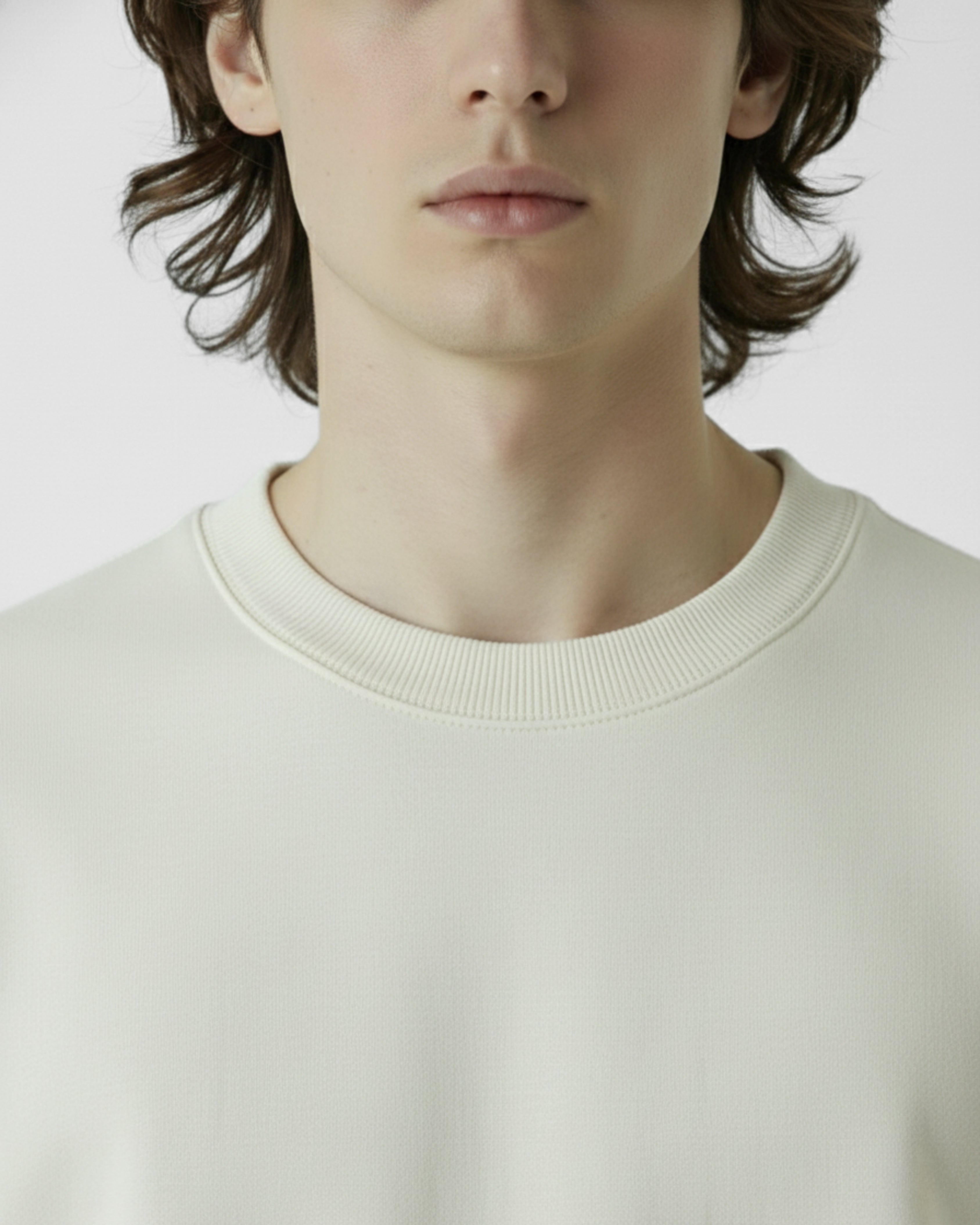 Close-up of a person wearing a light-colored sweater against a plain background